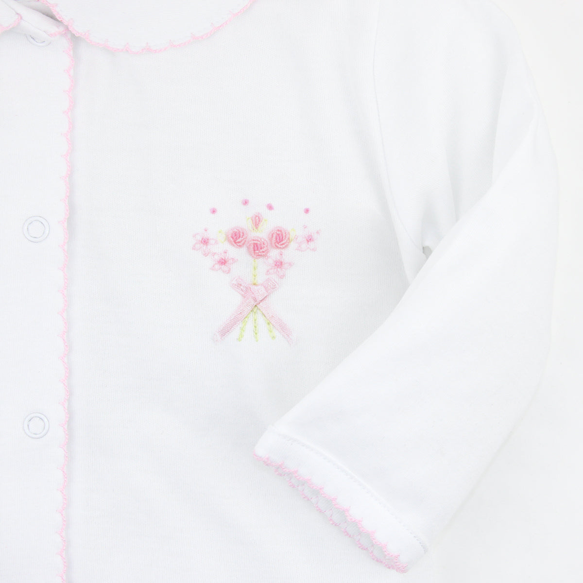 White baby girl footie with pink crochet on Peter Pan collar and snaps, floral bouquet embroidery on chest, and scattered tiny flowers.