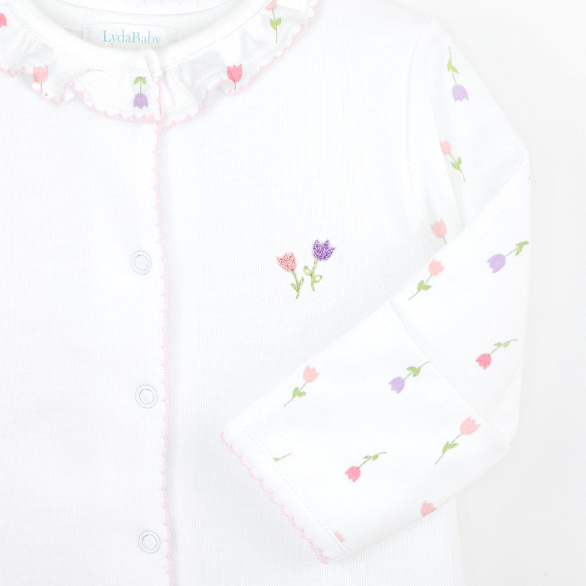 Delicate baby girl footie in premium Peruvian Pima cotton, with tulip print on sleeves and feet, and hand-embroidered tulip on the chest — soft, breathable, and beautifully crafted for newborn comfort.