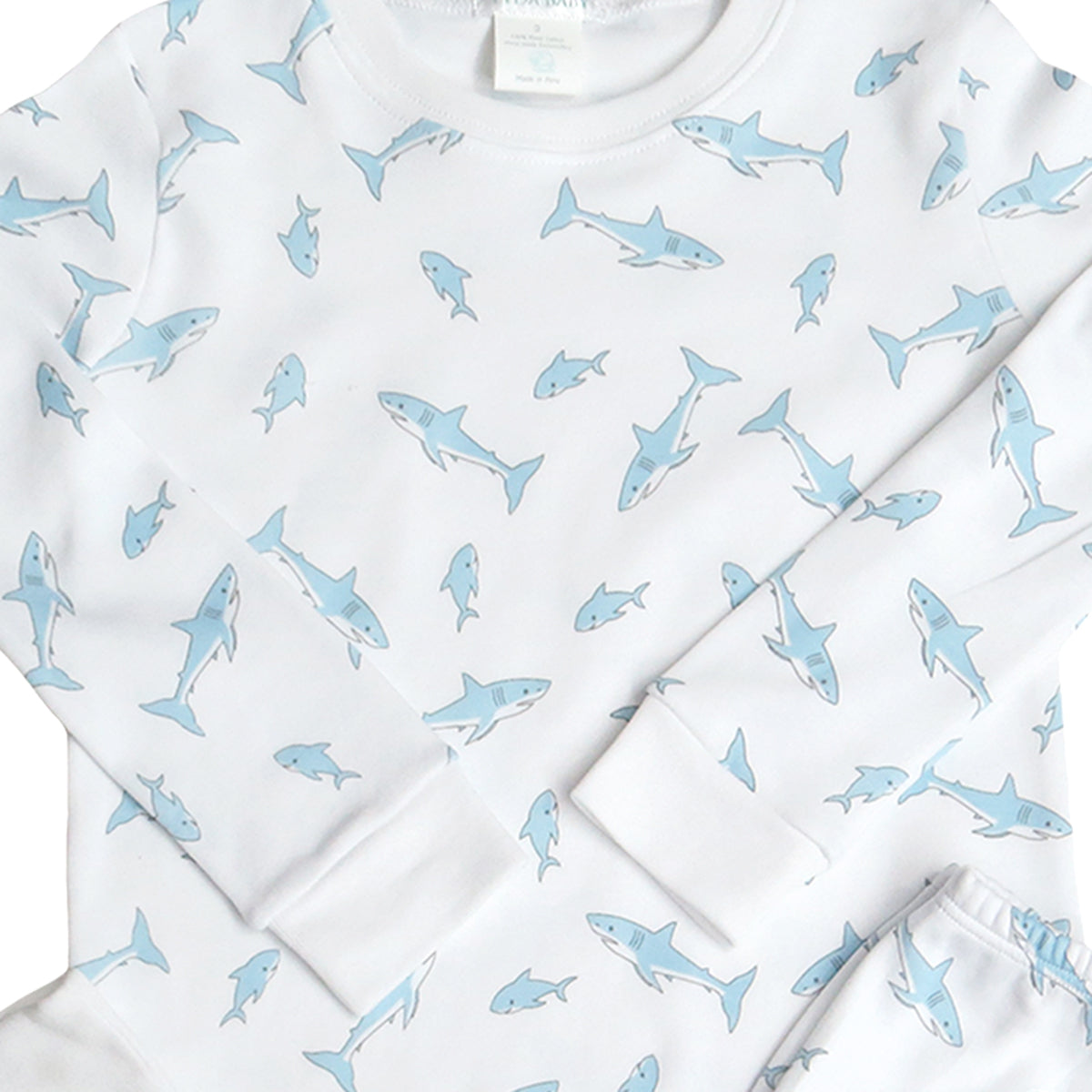 Close-up detail of a white pima cotton pajama shirt with blue shark patterns on it
