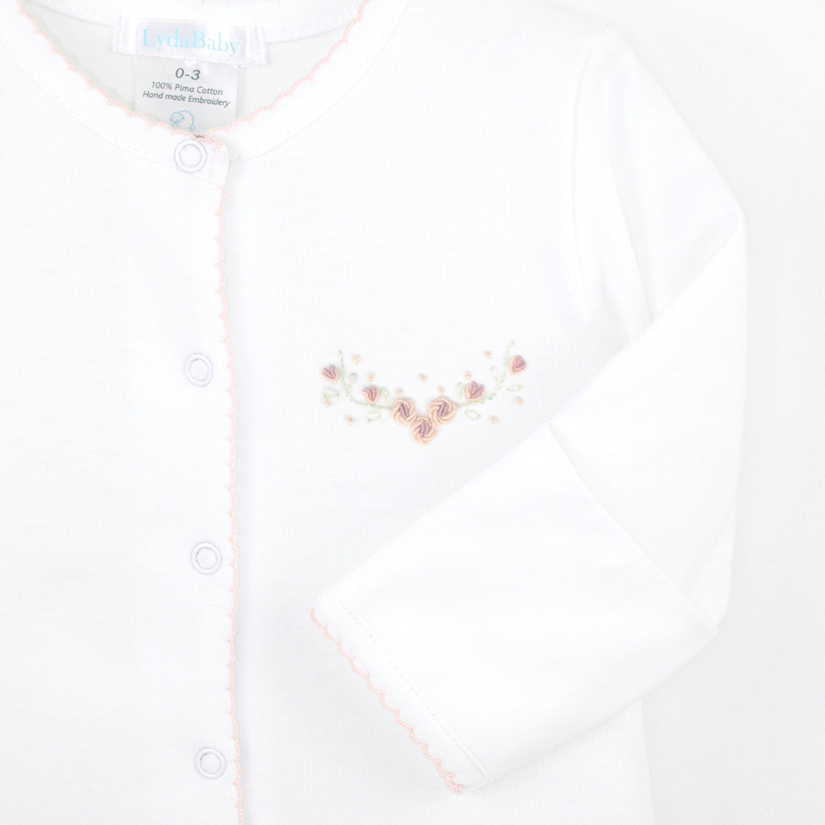 White luxury baby girl footie, Pima cotton, Peter Pan collar with pink crochet, hand-embroidered roses forming a V and scattered details.