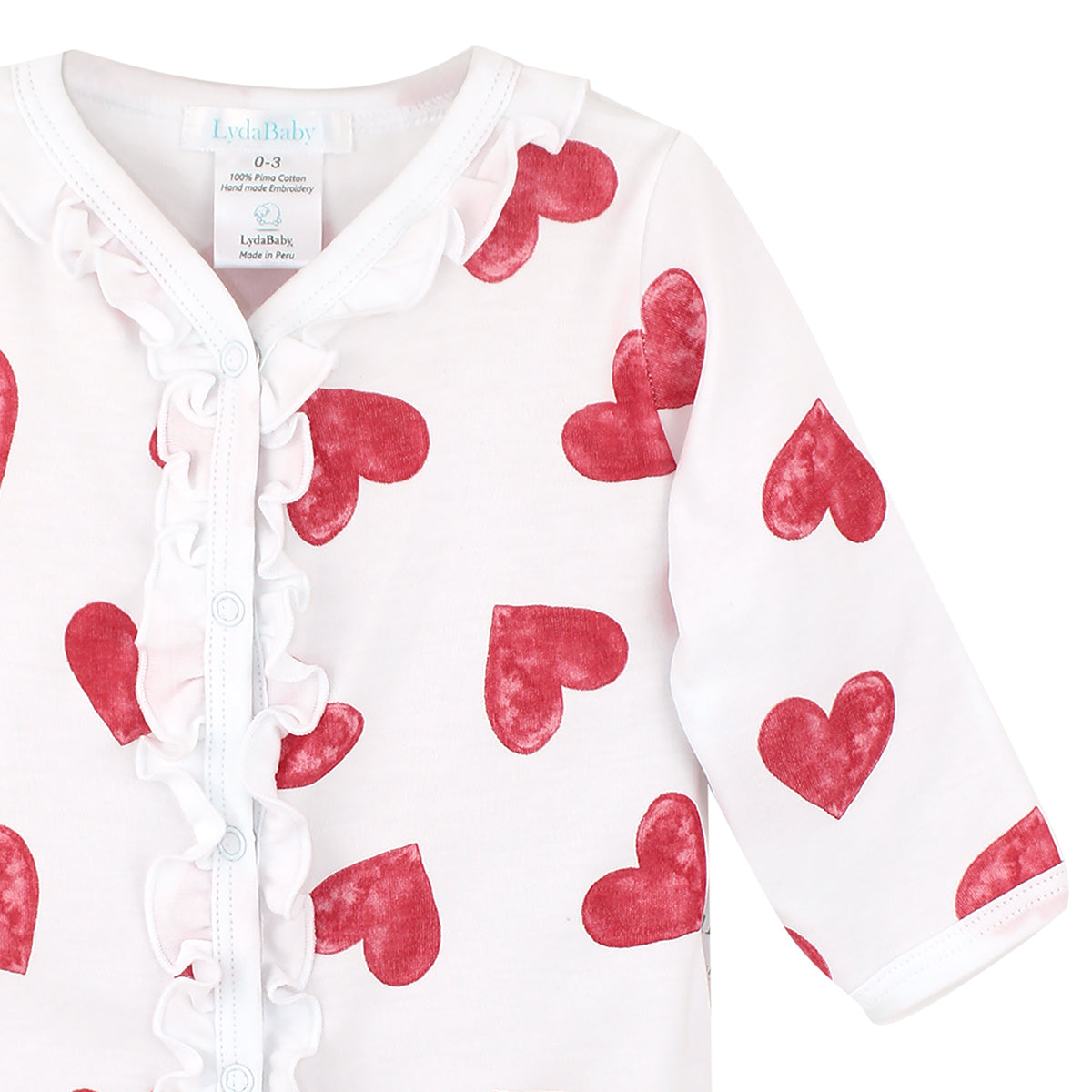 White baby girl footie made of Peruvian Pima cotton, with red watercolor heart print and ruffle trim on chest.